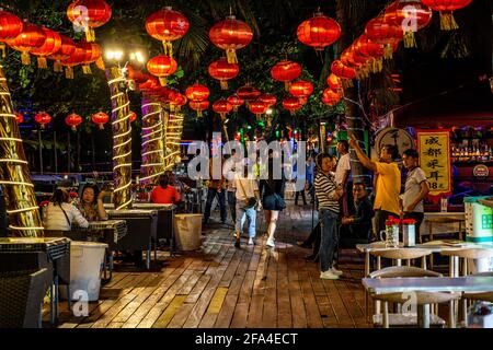 Sanya China , 25. März 2021 : Alley von Dadonghai Strandseite in der Nacht mit Restaurant und Bar Terrassen mit Menschen in Sanya Stadt Hainan Insel China Stockfoto