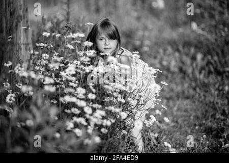 Porträt eines kleinen Mädchens zwischen Wildblumen. Schwarzweiß-Foto. Stockfoto