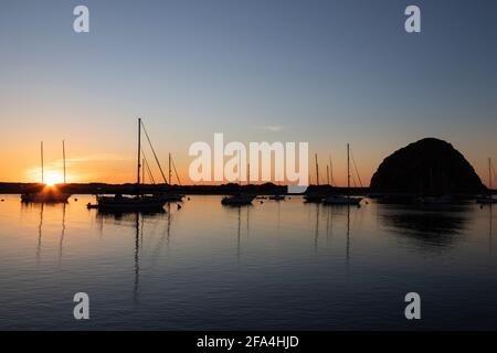 Ein auffälliger Sonnenuntergang im Winter zeigt die Boote, die im berühmten kalifornischen Morro Bay Harbour an der Central Coast festgemacht sind. Stockfoto
