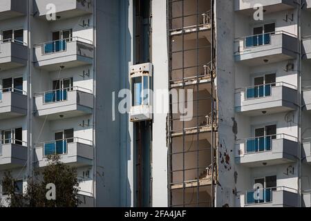 Ein altes verlassene Hotelgebäude mit kaputtem Glas, einem Aufzug auf der Straße, zerrissenen Klimaanlagen und Schildern in einem tropischen Land mit Palmen Stockfoto