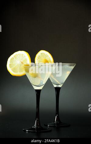 Zwei martini-Gläser mit weißem Wermut, Zitronenscheiben und Oliven auf schwarzem Hintergrund. Nahaufnahme. Stockfoto