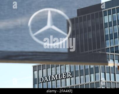 Stuttgart, Deutschland. April 2021. An einem Gebäude am Hauptsitz des Stuttgarter Automobilherstellers Daimler ist ein Daimler-Firmenlogo angebracht, im Vordergrund eine Flagge mit einem Mercedes-Stern. Die Quartalszahlen des Automobilkonzerns Daimler werden am 23. April bekannt gegeben. Quelle: Bernd Weißbrod/dpa/Alamy Live News Stockfoto