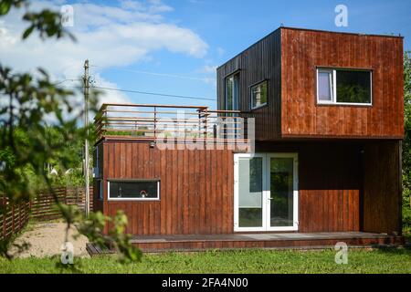 MINSK. WEISSRUSSLAND - MAI 2016: Blick auf das braune modulare Haus vor dem Hintergrund von Grün und blauem Himmel in den Wolken. Hochwertige Fotos Stockfoto