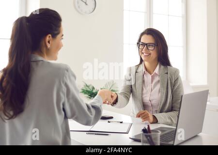 Glückliche junge Frauen treffen sich im Büro, machen einen Geschäftsabschluss und schütteln die Hände Stockfoto