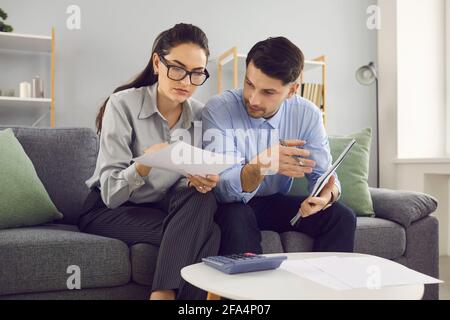 Das verheiratete Paar analysiert und berechnet seine Finanzkonten, während es auf der Couch sitzt. Stockfoto