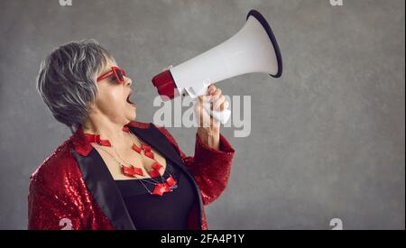 Funky exzentrische ältere Frau brüllt in einem Megaphon und kündigt eine an Verrückter Blowout-Verkauf Stockfoto