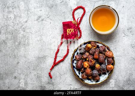 Beliebte Speisen während Iftar - trockene Datteln. Karan, Rosenkranz auf betonem Hintergrund Draufsicht Flat Lay Muslim Holiday of Holy Month of Ramadan Stockfoto