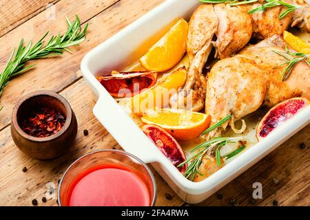 Gegrilltes Hähnchenfleisch mit Orangensauce und Rosmarin auf rustikalem Holztisch.hausgemachtes Essen Stockfoto