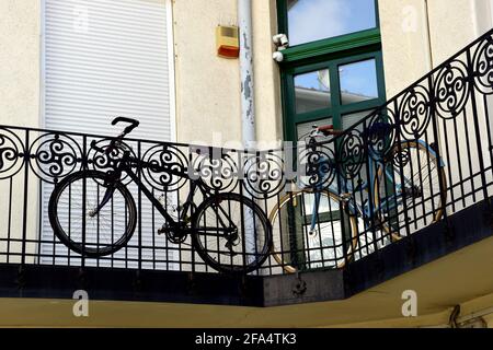 Fahrräder geparkt und gelagert entlang alten europäischen Wohngebäude außen Koridor. Verziertes schwarzes schmiedeeisernes Geländer. Grün bemalte Eingangstür. Stockfoto