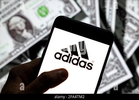 China. April 2021. In dieser Fototafel ist das deutsche multinationale Sportbekleidungslogo der Marke Adidas auf einem Android-Handy-Bildschirm mit der Währung des US-Dollar-Symbols, dem Dollar-Symbol im Hintergrund, zu sehen. (Foto von Budrul Chukrut/SOPA Images/Sipa USA) Quelle: SIPA USA/Alamy Live News Stockfoto