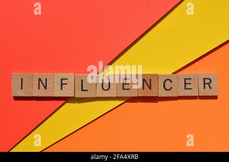 Influencer, Wort in Holzalphabet-Buchstaben isoliert auf hellrotem, gelbem und orangefarbenem Hintergrund Stockfoto