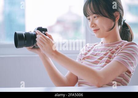 Junge asiatische Frau schaut sich das neu aufgenommene Foto an Kamera Stockfoto