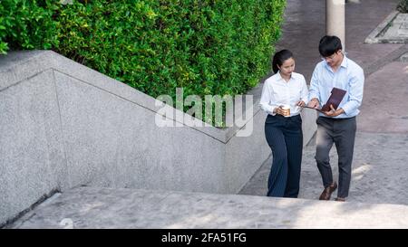 Geschäftskollegen diskutieren im Freien in der Nähe des Bürogebäudes über Arbeitsfragen und unterhalten sich im Freien miteinander Stockfoto