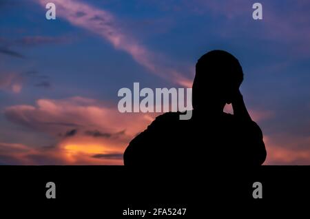 Silhouette des asiatischen Mannes allein bleiben mit Dämmerung Himmel Hintergrund. Depression und psychische Gesundheit Konzept. Stockfoto