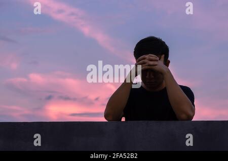 Asian miserable depressiven Mann bleiben allein mit Himmel Hintergrund. Depression und psychische Gesundheit Konzept. Stockfoto