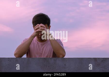 Asian miserable depressiven Mann bleiben allein mit Himmel Hintergrund. Depression und psychische Gesundheit Konzept. Stockfoto