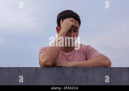 Asian miserable depressiven Mann bleiben allein mit Himmel Hintergrund. Depression und psychische Gesundheit Konzept. Stockfoto