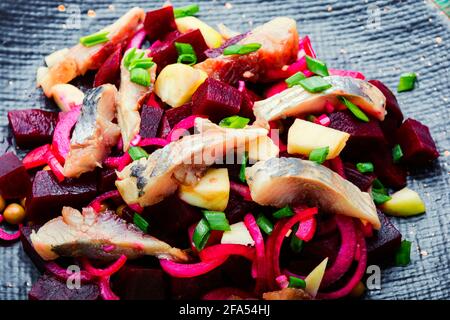 Salat mit gesalzenem Hering, Rüben, Zwiebeln und grünen Erbsen Stockfoto