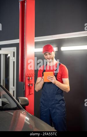 Automechaniker, der sich das Tablet in der Nähe des Autos ansieht Stockfoto