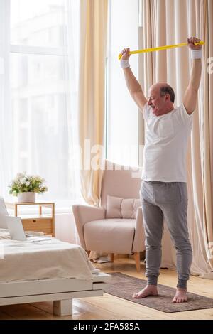 Senior hispanic Mann Training zu Hause auf Selbstisolation Training Zu Hause mit einem Gummizug Stockfoto