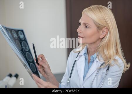 Denkende aufmerksame Ärztin mit MRT-Scan in der Hand Stockfoto