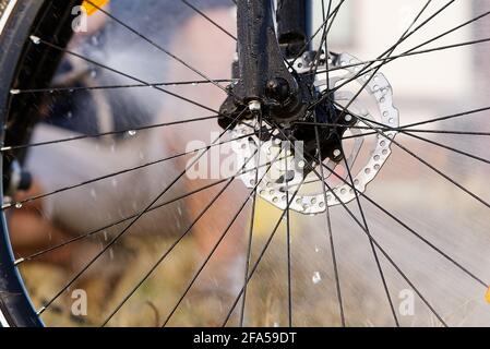 Fahrradspülung auf dem Hinterhof. Frühlingsvorbereitungen für die Radsaison. DIY Bike Pflege, Druck Fahrrad waschen Stockfoto