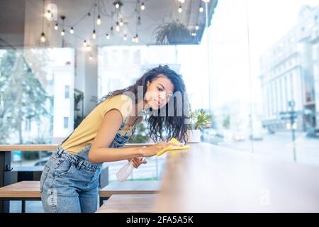 Ernsthaft aussehende Frau, die den Tisch im Café sauber wischte Stockfoto