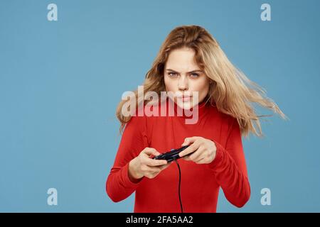Hübsche Frau in rot Pullover Joystick Controller Set-Top-Box blau Hintergrund Stockfoto