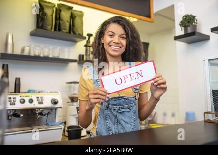 Frau am Barschalter mit Schild, auf dem steht: Offen Stockfoto