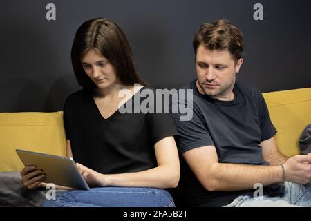 Guy eifersüchtig schaut in Freundin Tablet zu sehen, wer sie Chattet mit Stockfoto