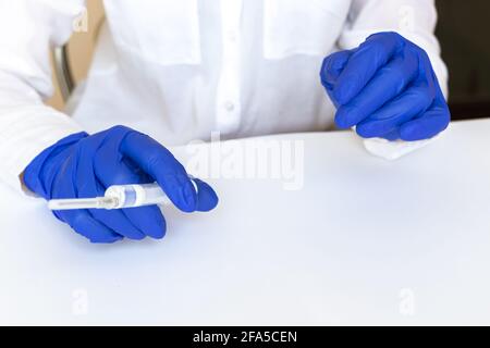 Arzt im weißen Kleid im Krankenhaus in blauen medizinischen Handschuhen mit Spritze, Vorbereitung Konzept Foto Stockfoto