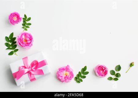 Geschenk und rosa Rosenblüten auf weißem Hintergrund. Muttertag . Frauentag. Flach liegend, Draufsicht, Kopierbereich Stockfoto