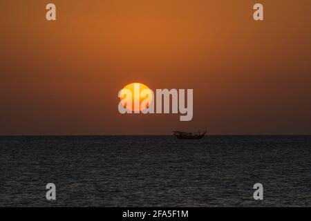Sonnenuntergang am Arabischen Meer mit Daus, die auf dem Wasser schwimmen, von der Südspitze der Insel Masirah, Oman aus gesehen Stockfoto