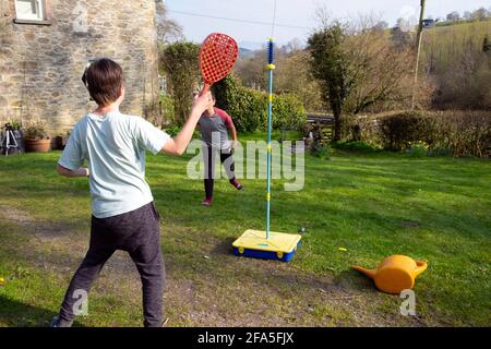 Zwei Jungen 11 Jahre spielen Swingball mit Fledermäusen in einem Ländlicher Garten im Frühjahr nach Lockdown Einschränkungen Leichtigkeit 2021 Carmarthenshire WALES UK KATHY DEWITT Stockfoto