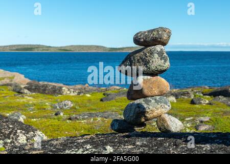 Eine Steinpyramide auf dem Hintergrund der Küste des Weißen Meeres an einem sonnigen Tag. Das Konzept der Lebensbalance, Harmonie und Meditation. Eine unvergessliche Anmeldung Stockfoto