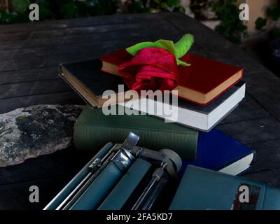 Eine Rose auf einem Stapel von Büchern und Eine Schreibmaschine Stockfoto