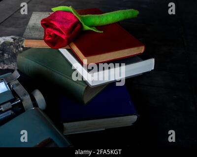 Eine Rose auf einem Stapel von Büchern und Eine Schreibmaschine Stockfoto