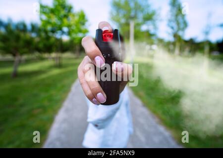 Frau, die Pfefferspray oder Tränengas zur Selbstverteidigung verwendet Im Freien Stockfoto