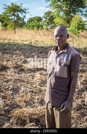 Landwirt in Malawi steht neben seinem schützenden Landwirtschaftsfeld Stockfoto