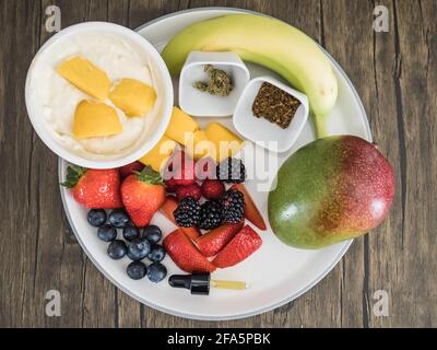 Gesunder Obstsalat mit medizinischem Cannabisöl, einige Menschen bekommen starkes cbd, Öl, andere verwenden THC-Cannabistinktur Stockfoto