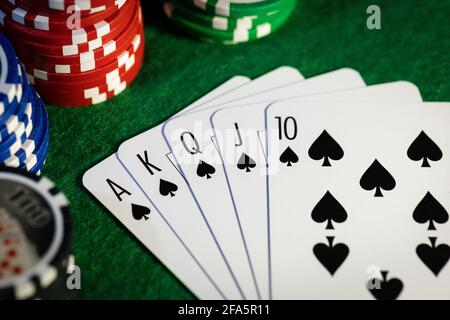 royal Flush im Pokerspiel. Karten mit Casino-Chips auf grünem Tuch Stockfoto