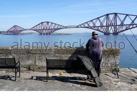 South Queensferry, Schottland, Großbritannien. April 2021. Klar warm und sonnig an der South Queensferry. Menschen, die das Beste aus dem guten Wetter machen und beginnen, die Natur an den üblichen Besucher-Hotspots zu besuchen und zu genießen. Angeln am Pier. Kredit: Craig Brown/Alamy Live Nachrichten Stockfoto