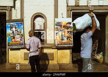 Mumbai, Maharashtra, Indien: Zwei Männer gehen an einem kleinen Kino vorbei, das Bollywood-Filme im Viertel Byculla spielt. Stockfoto