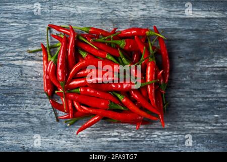 Blick aus der Höhe auf einige rote Chilischoten, die in angeordnet sind Eine Blockform auf einem grauen rustikalen Holztisch Stockfoto