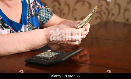 Kleines Rentenkonzept. Die Frau zählt auf den Dollar. Stockfoto