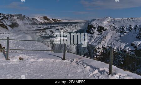 Blick auf den mächtigen Wasserfall Gullfoss (Isländisch: goldener Wasserfall) im Südwesten Islands, Teil des berühmten Goldenen Kreises, im Winter mit Zaun davor. Stockfoto