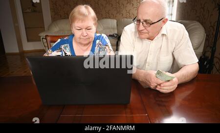Ältere Ehepaare, die am Computer sitzen, kaufen im Internet ein. Stockfoto