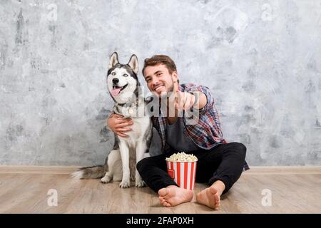 Junger bärtiger Mann, der mit seinem Husky-Hund hinausgehängt hat. Hipster-Mann trägt kariertes Flanell-Shirt und graues Tank-Top verbringen hochwertige Zeit mit vier l Stockfoto