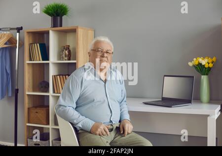 Alter älterer kaukasischer Mann am Tisch, der am Tisch sitzt Heimbüro Stockfoto