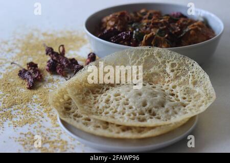 Trichter aus Füchsschwanzmilchetten. Eine experimentelle Version eines beliebten Kerala-Gerichts namens Appam serviert mit Kerala-Chicken-Kerridhuly, das mit zu Hause zubereitet wird Stockfoto